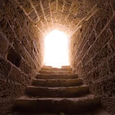 A stone stairway leading up to a bright doorway.